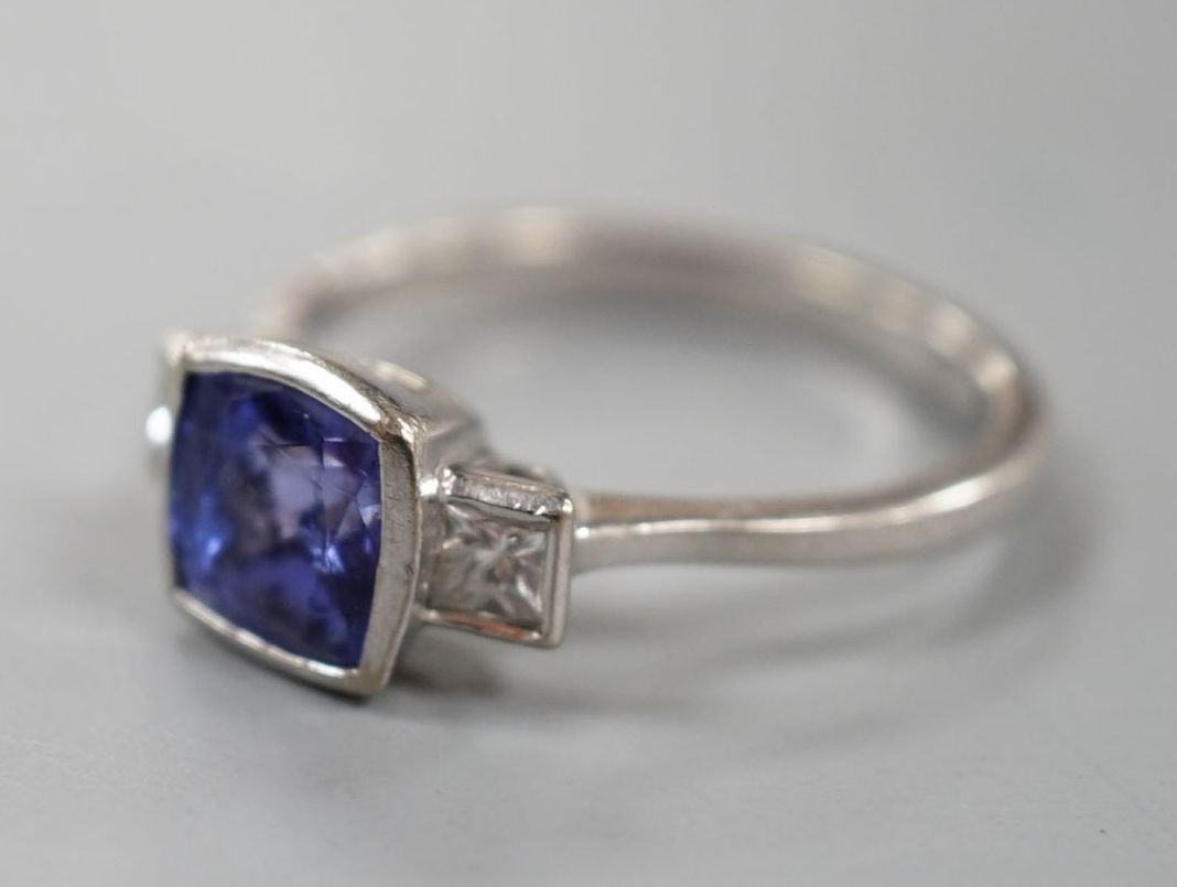 A modern 18ct white gold, single stone tanzanite and two stone diamond set ring, size R, gross weight 5 grams.